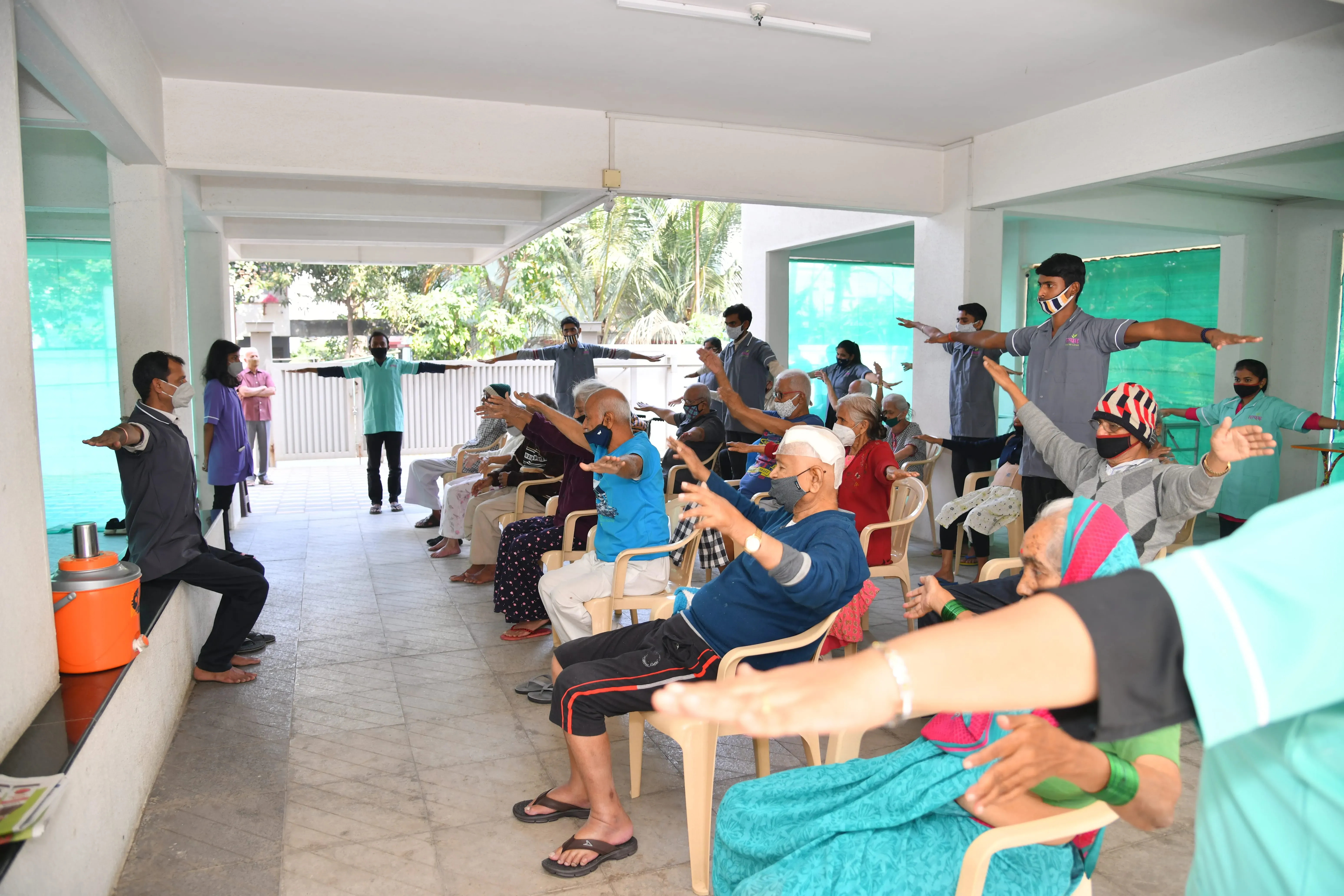 Residents doing seated stretching exercises with staff