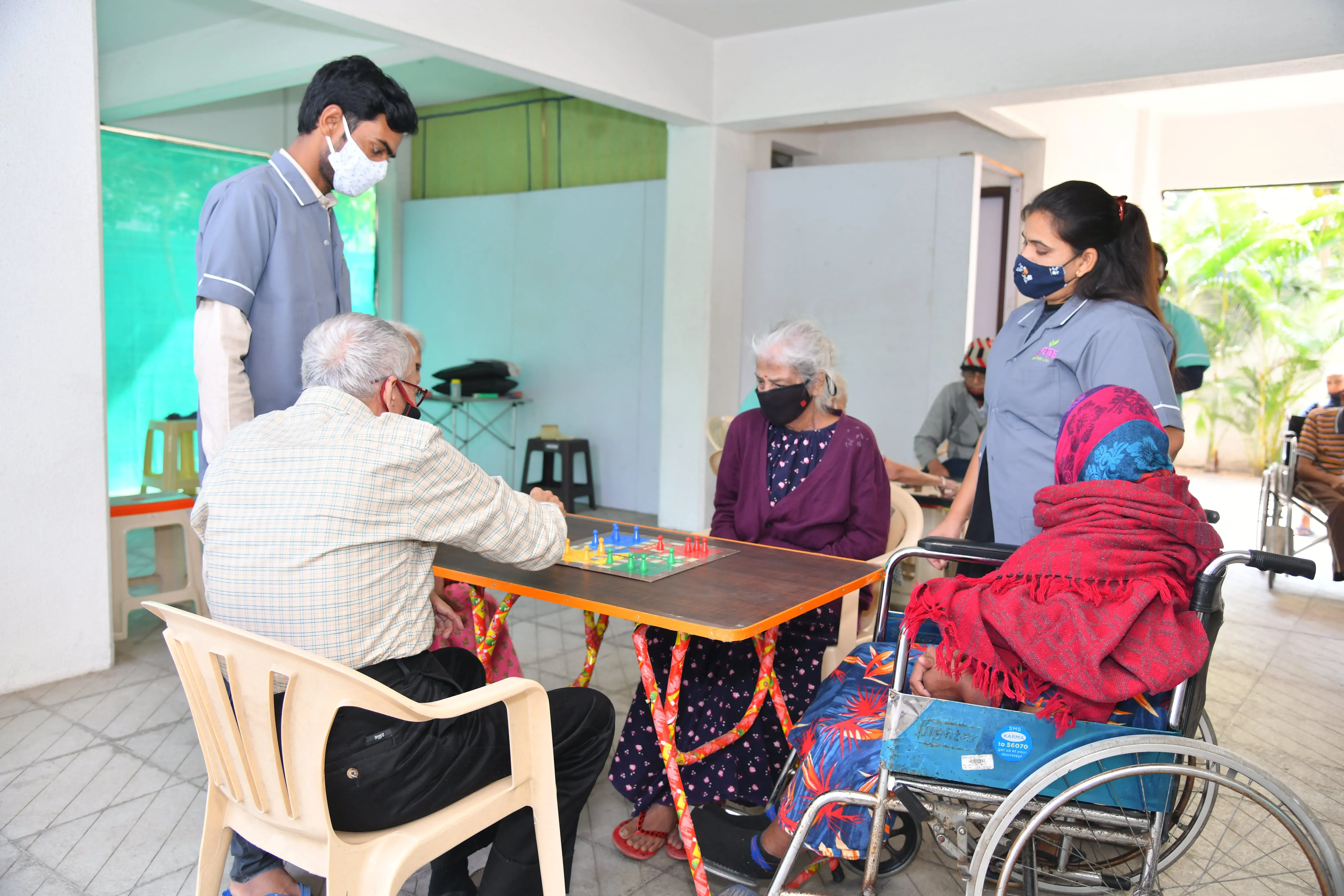 Residents playing ludo with two members of staff