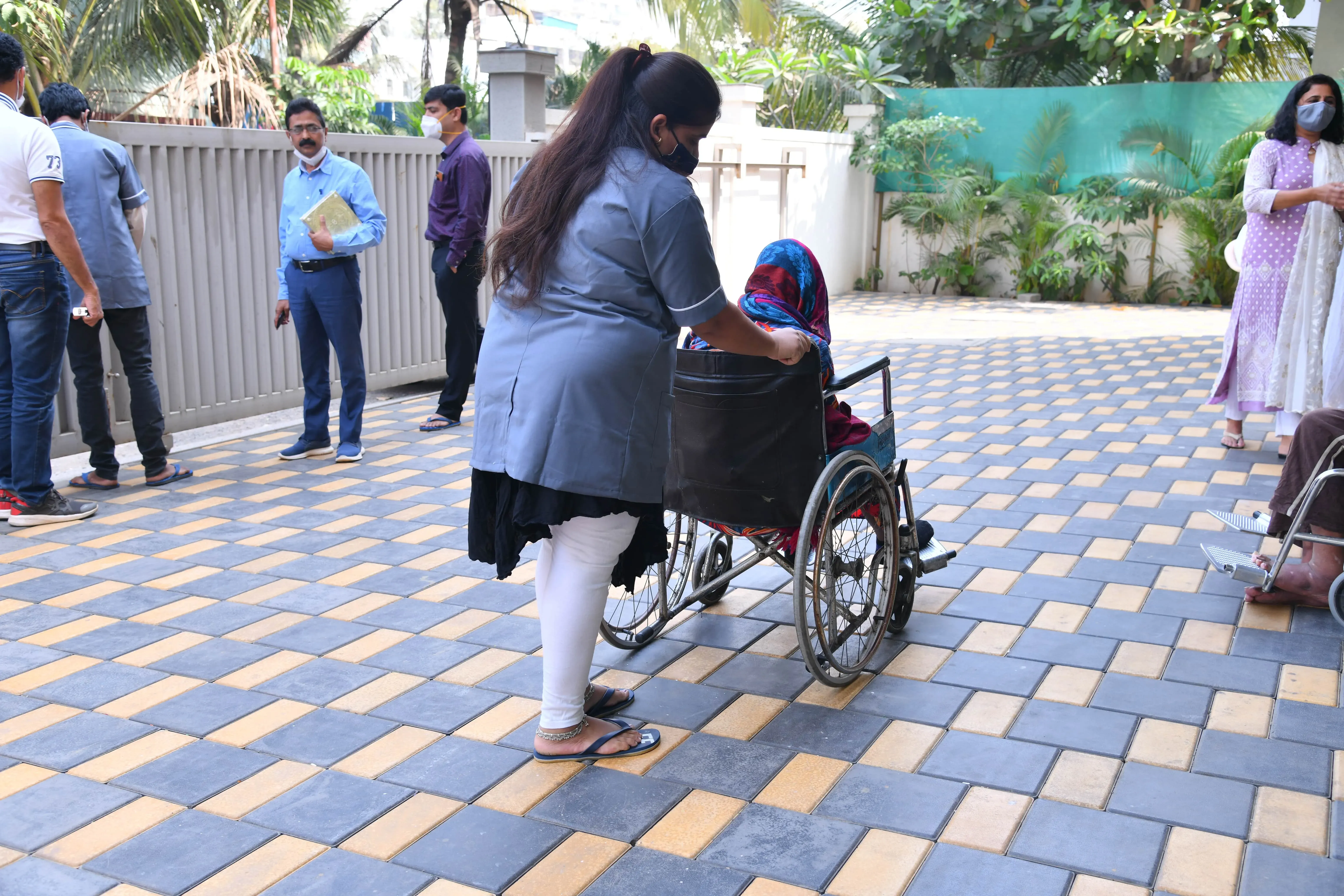 A carer wheeling a resident across the courtyard
